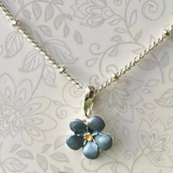 Necklace with a blue flower pendant on a floral patterned background