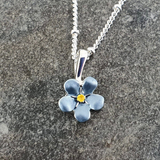 Blue flower pendant necklace on a gray stone surface