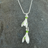 Silver necklace with two white flower pendants on a gray stone background