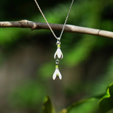 Necklace with floral pendants on a branch against a green background