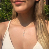 Woman wearing a delicate necklace with a small pendant outdoors